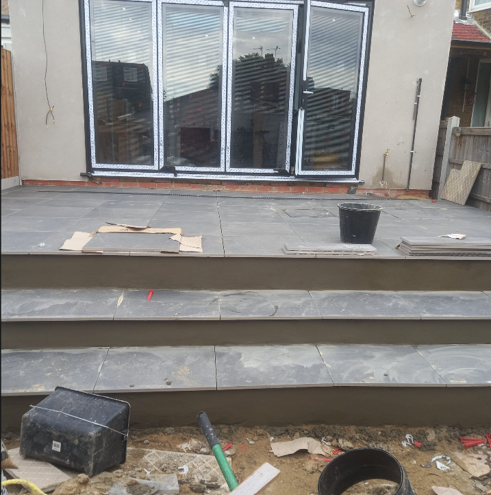 Porcelain paved patio with stone steps leading to bifold doors
